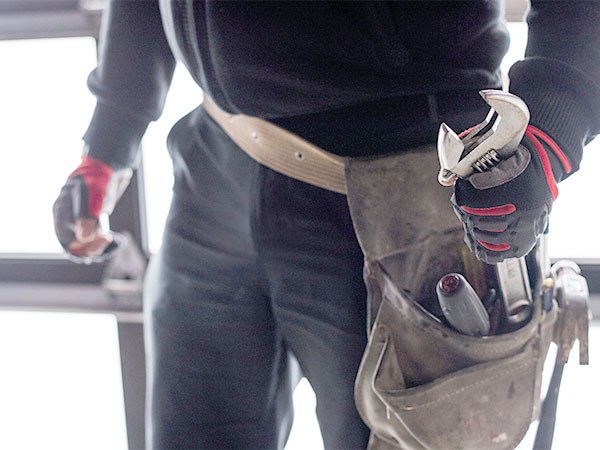 Plumber with a tool belt and wrench on a job, from the B. Spontak website