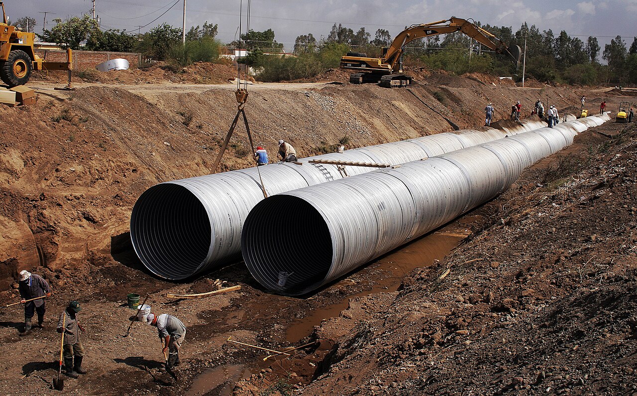 Crew installing large-diameter pipes in a trench