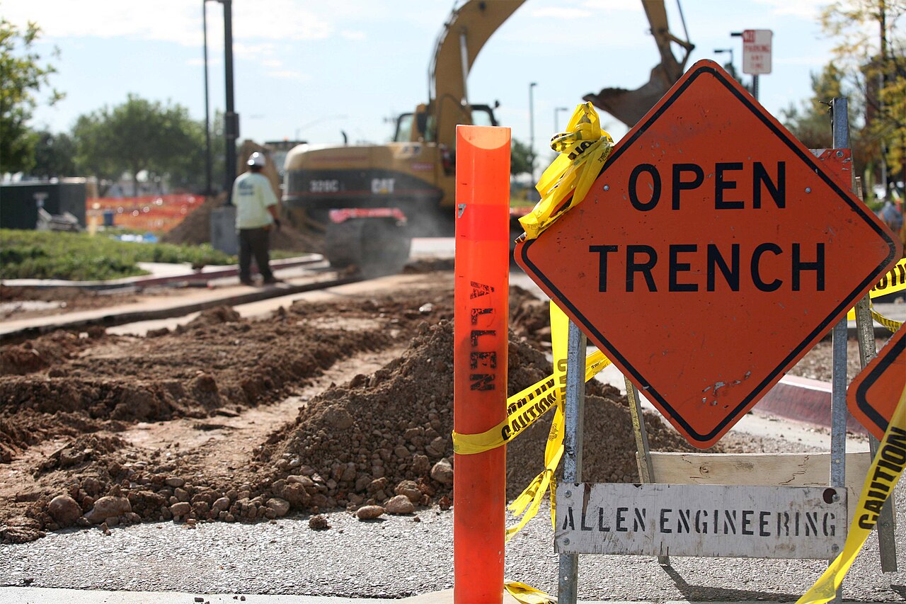 Open trench roadworks with an excavator on a commercial site